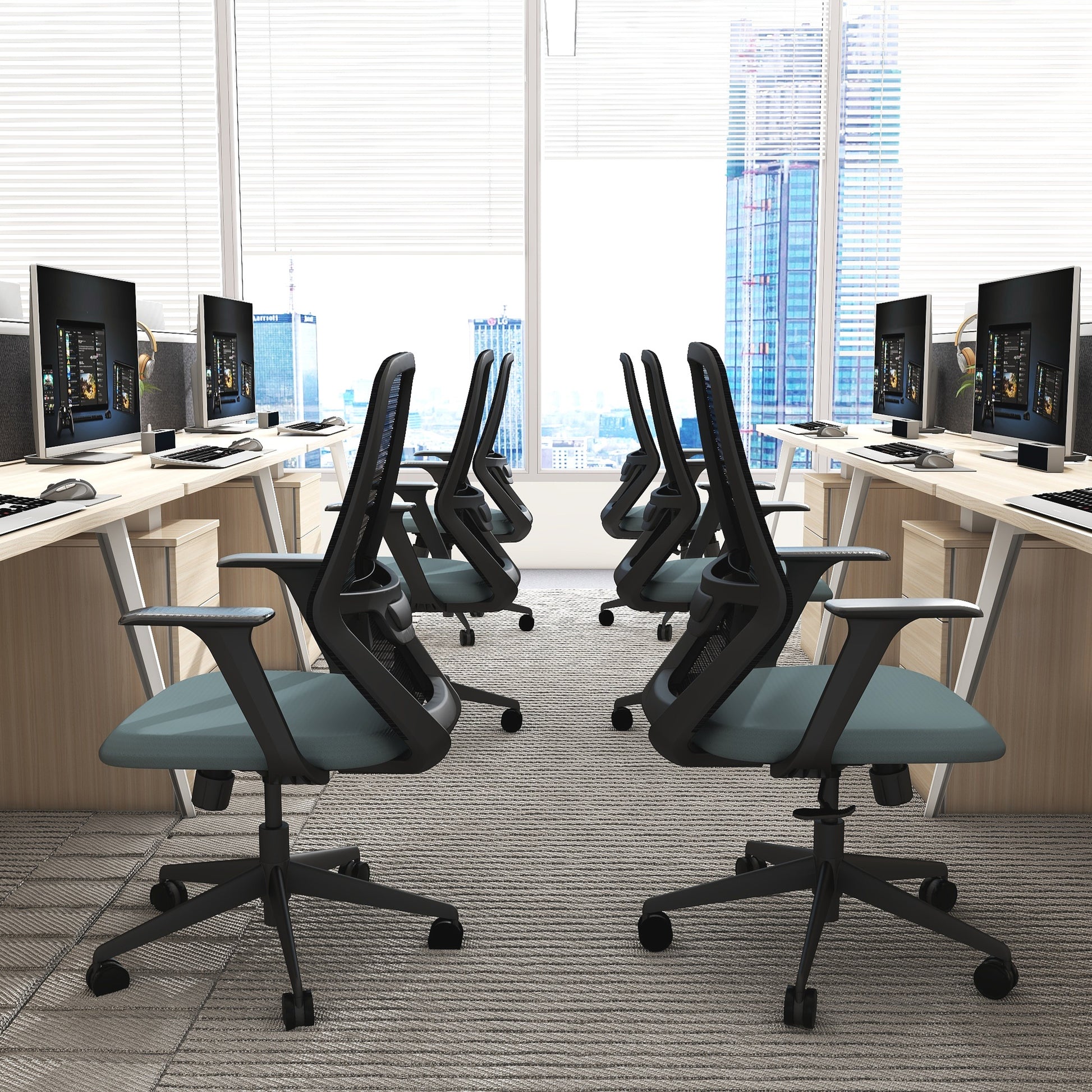 Modern office setup with desks, chairs, and computer monitors in a bright room.