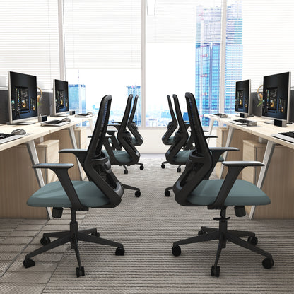 Modern office setup with desks, chairs, and computer monitors in a bright room.