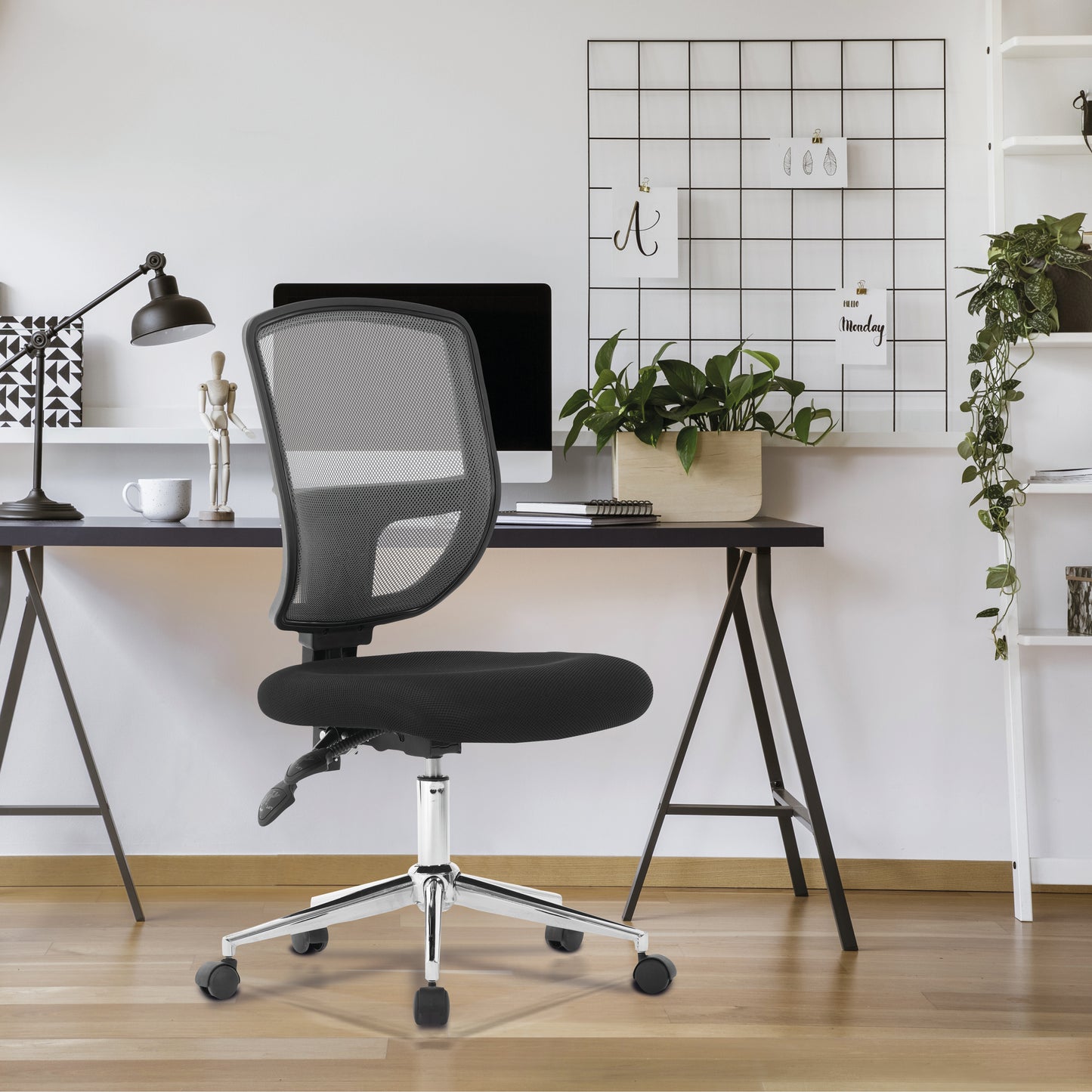 Black office chair in front of a desk with a computer and decor items in a home office setting.