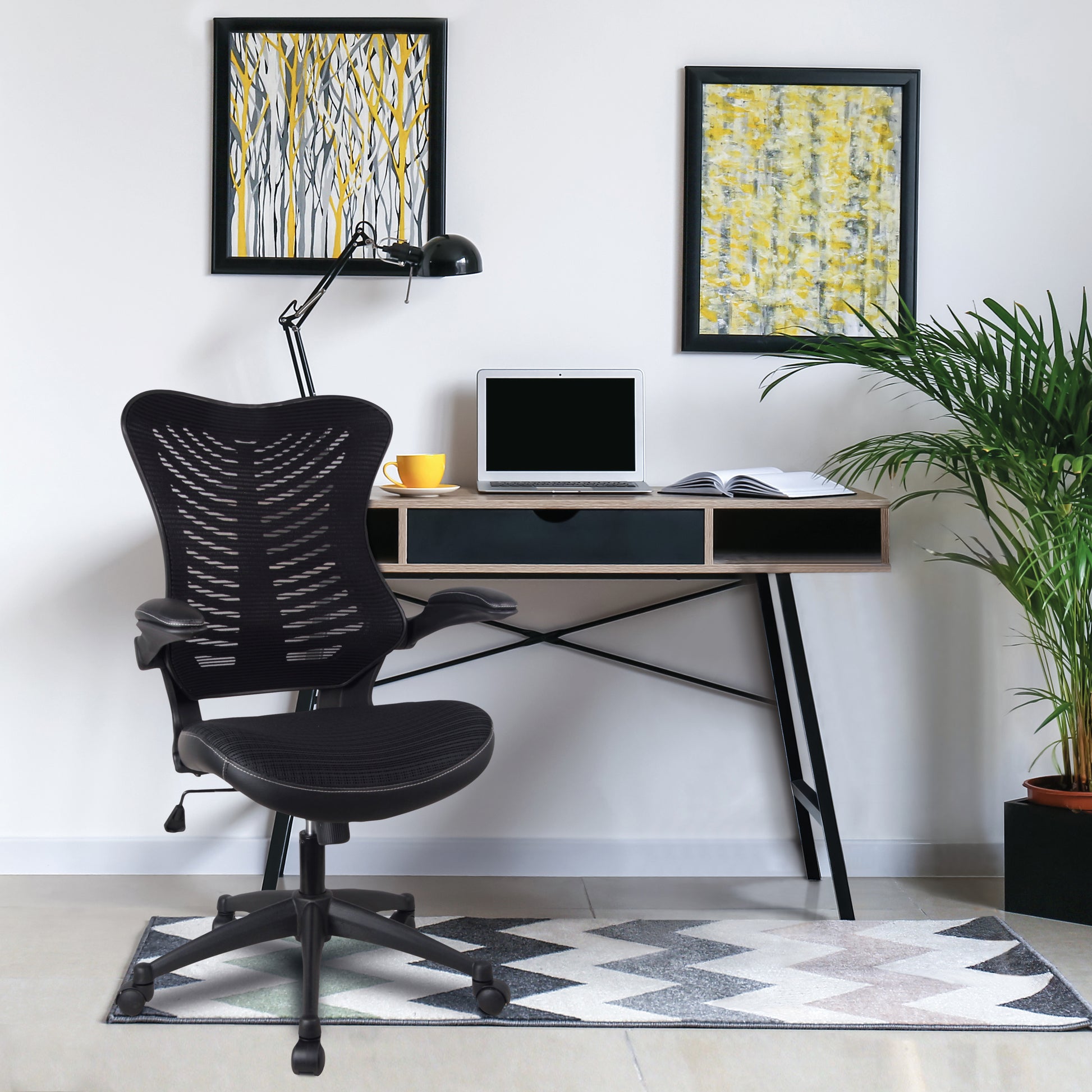 Modern office setup with a black chair, desk, laptop, and decor elements.