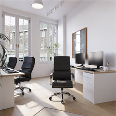 Modern office setup with desks, chairs, and computer monitors in a bright room.