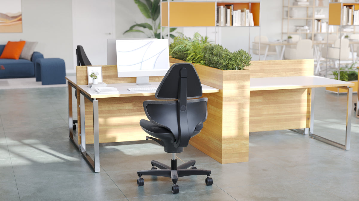 CoreChair Elite at a desk in an open-plan office, seen from behind with its high back pad